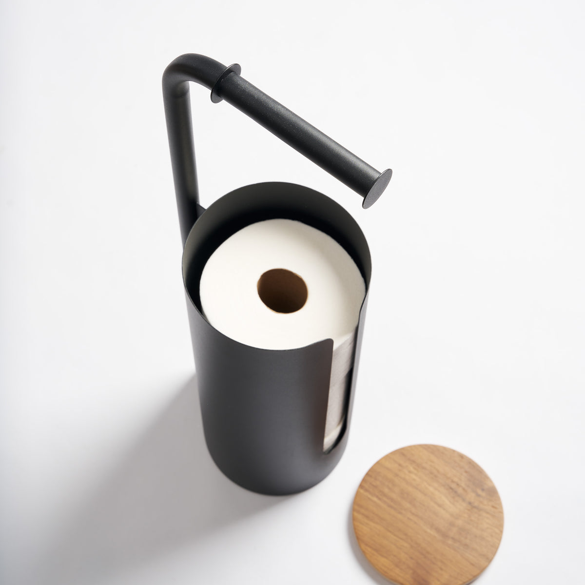 Apto Aloft Toilet Paper Stand with Storage in black with the wood lid off, showing a spare roll stored inside the steel canister