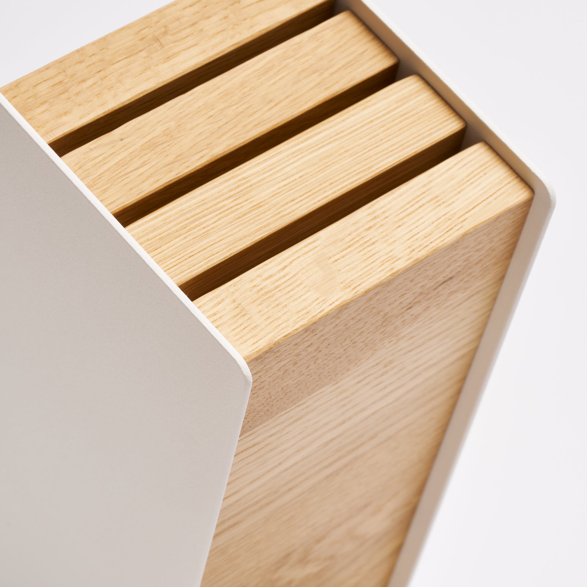 Close up of universal knife block with ash wood blocks and white steel frame from Apto. 