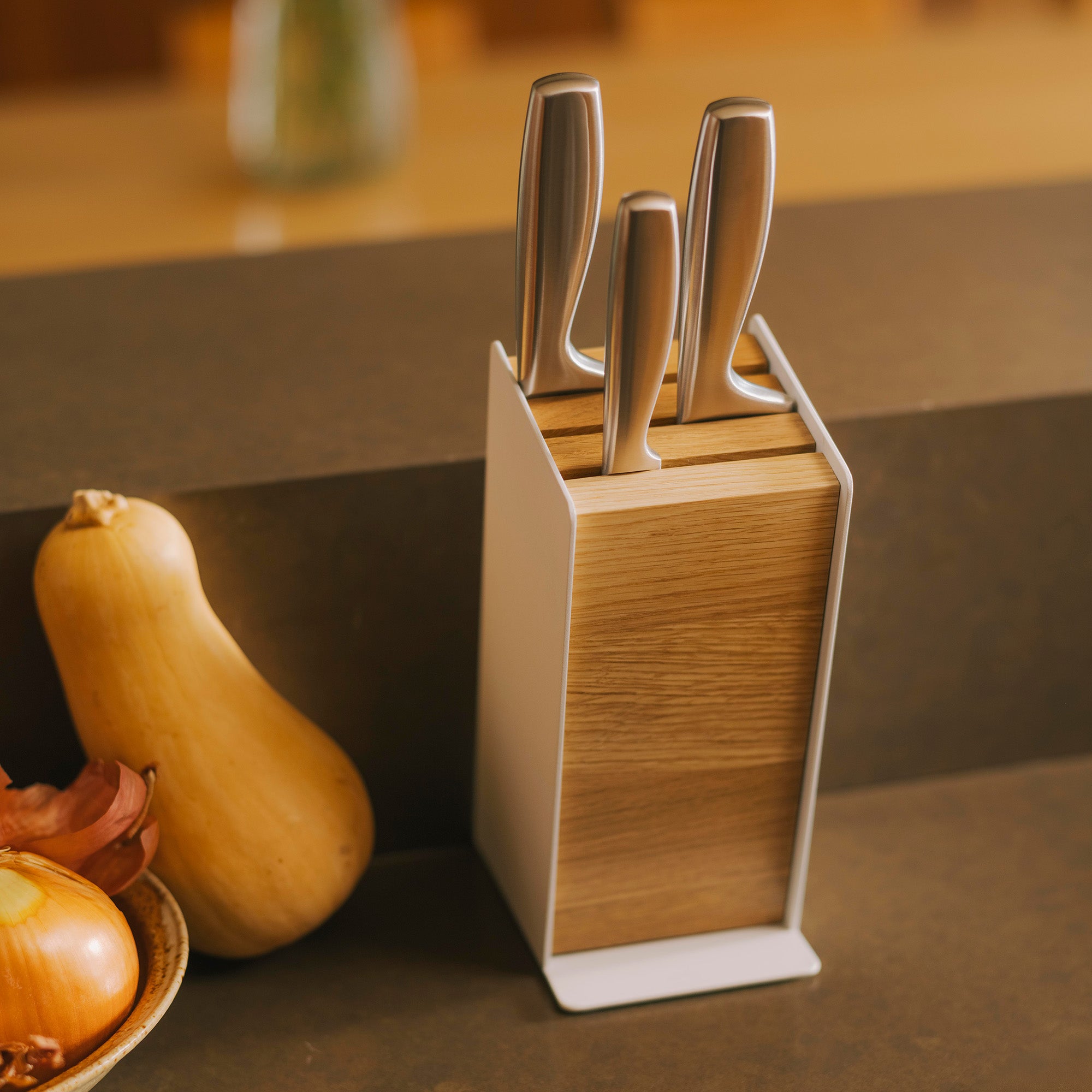 Universal knife block holding three knives of various sizes in a modern kitchen.