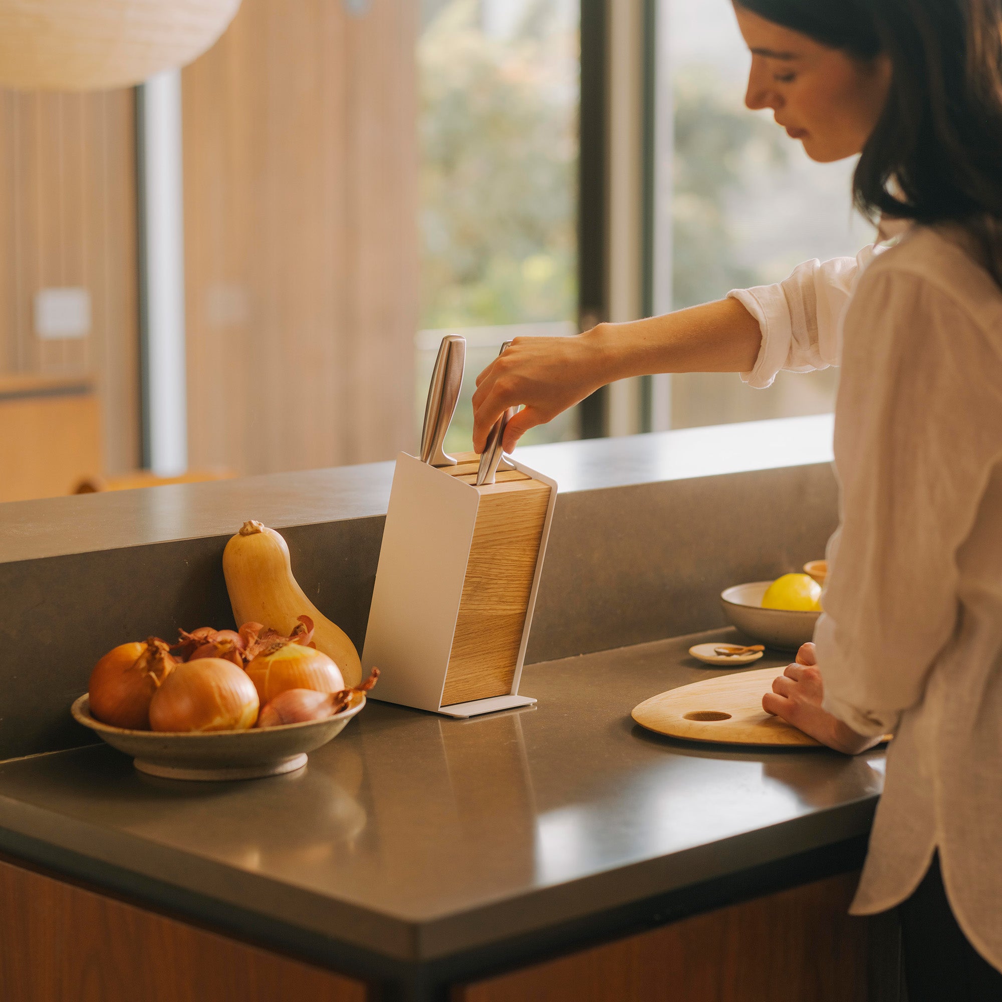 Woman removing knife from modern universal knife block from Apto in a modern kitchen. 