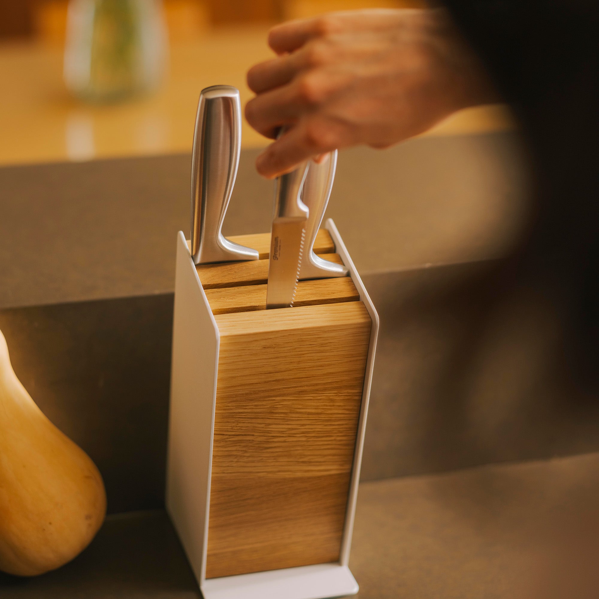 Hand removes a small knife from a universal knife block from Apto. 