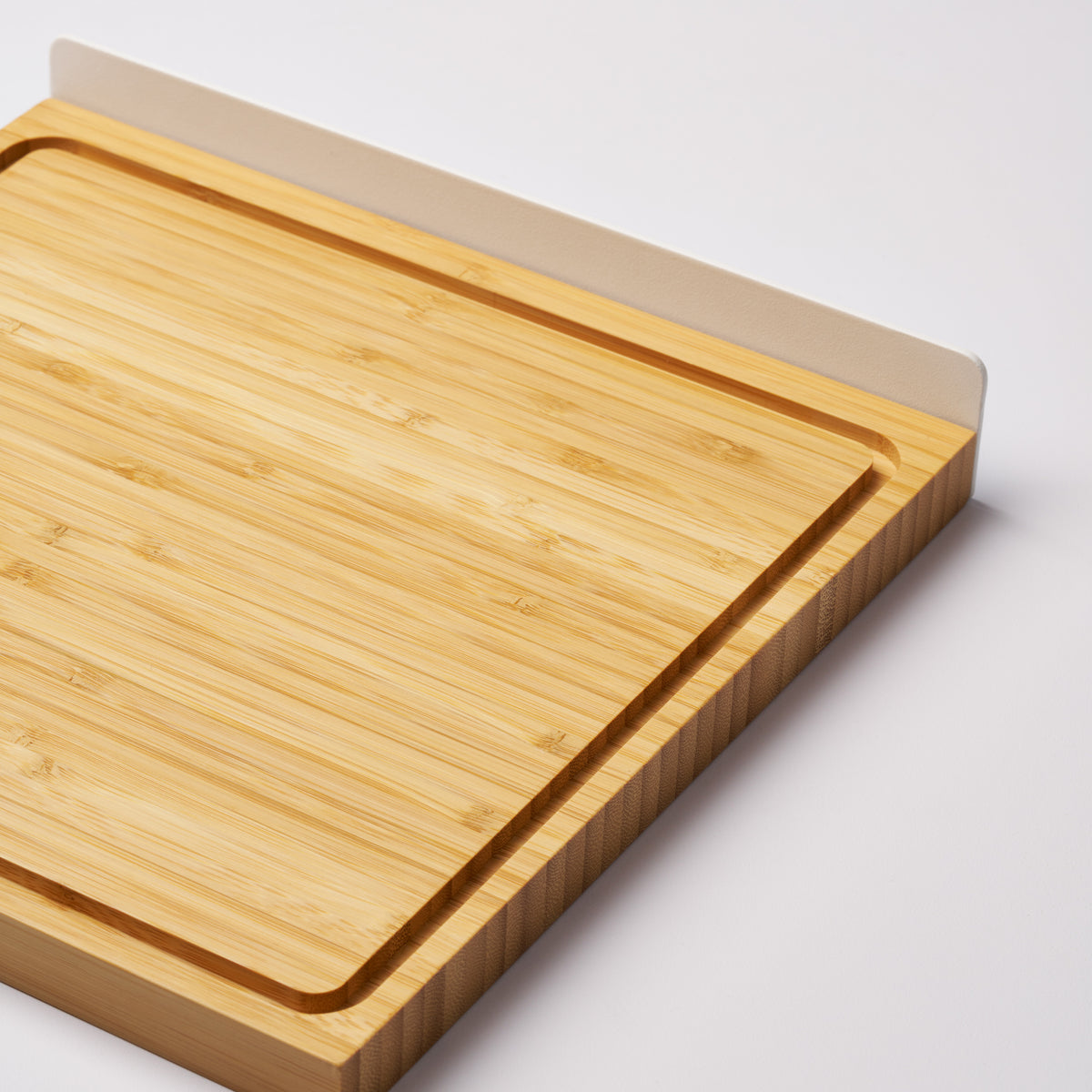 Bamboo cutting board with steel handle removed from the Slot knife stand to show functionality. Designed by Apto.