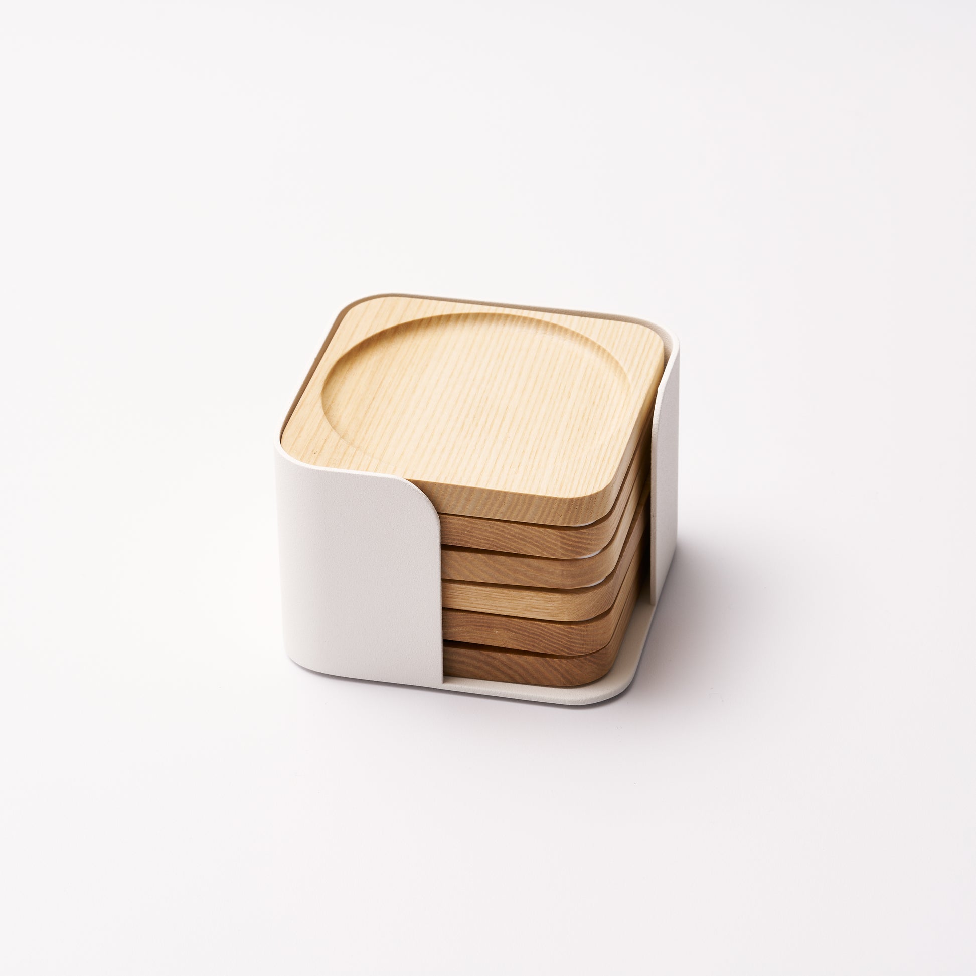 Six natural wood coasters held by a white steel organizer on a white background. Designed by Apto. 