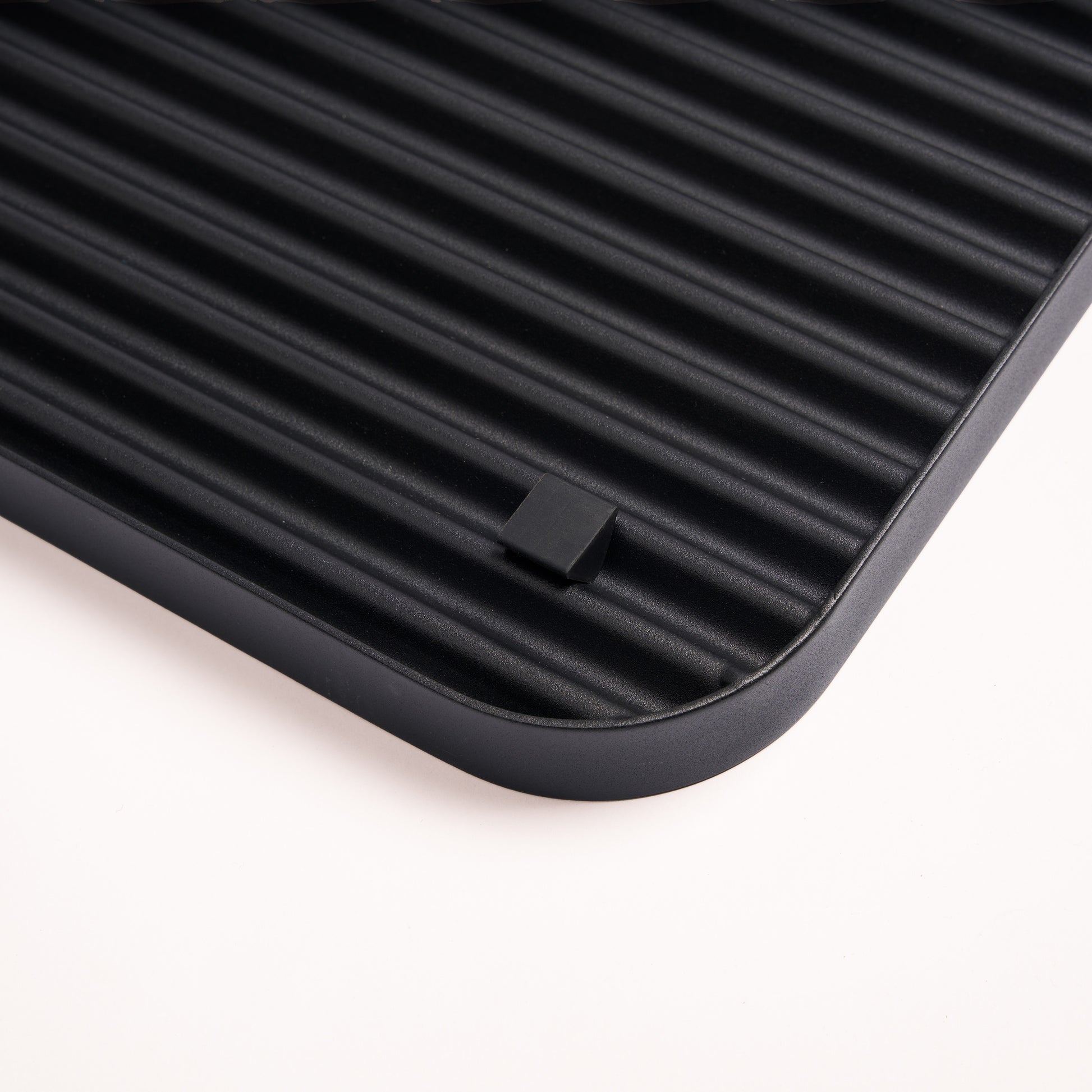Silicone footer for stability and floor protection on the bottom of the black steel boot tray from Apto.