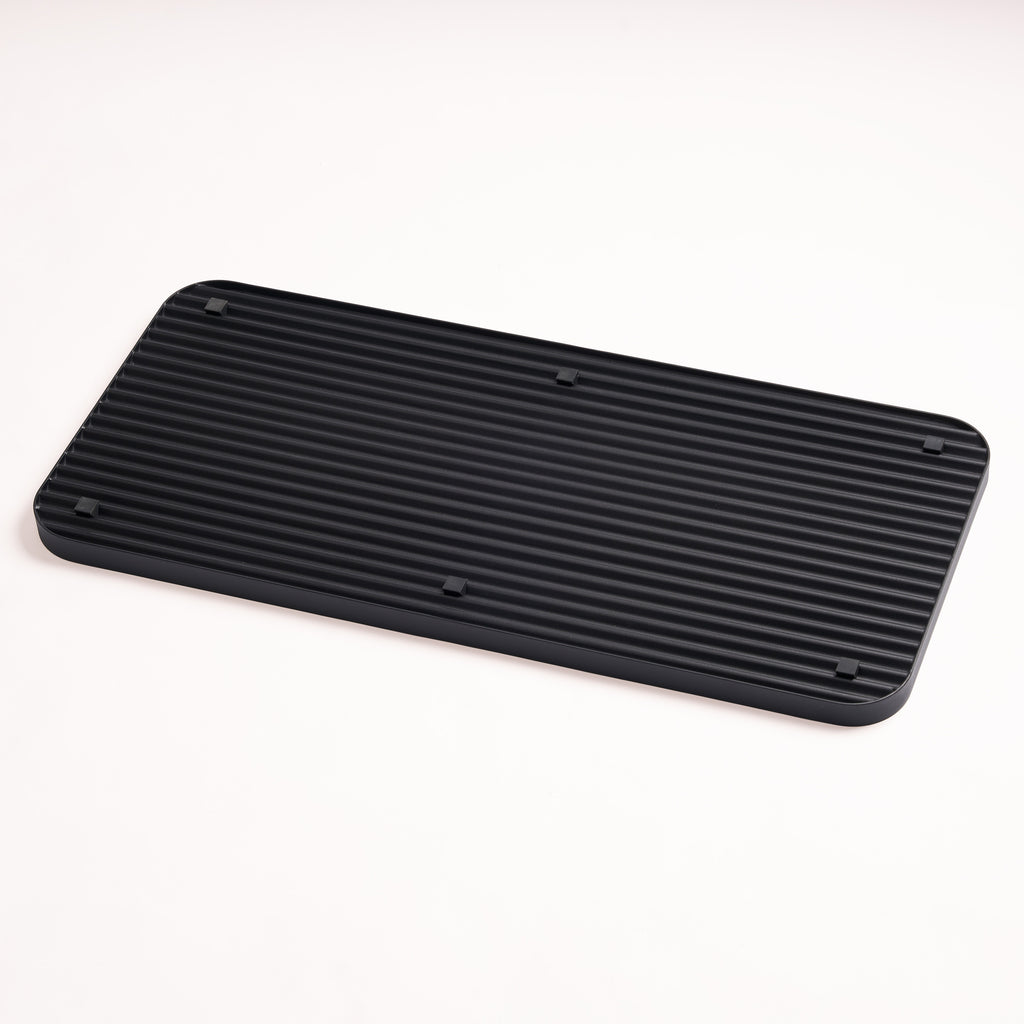 Four silicone footers for stability and floor protection on the bottom of the black steel boot tray from Apto.