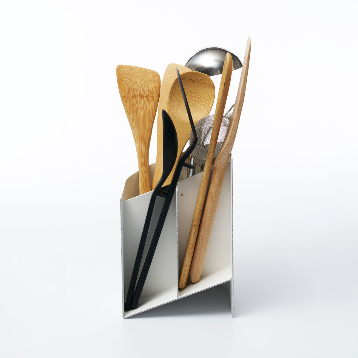 Side view of Sloped Utensil Holder, shown in a cutaway view revealing its compartments with assorted cooking utensils.