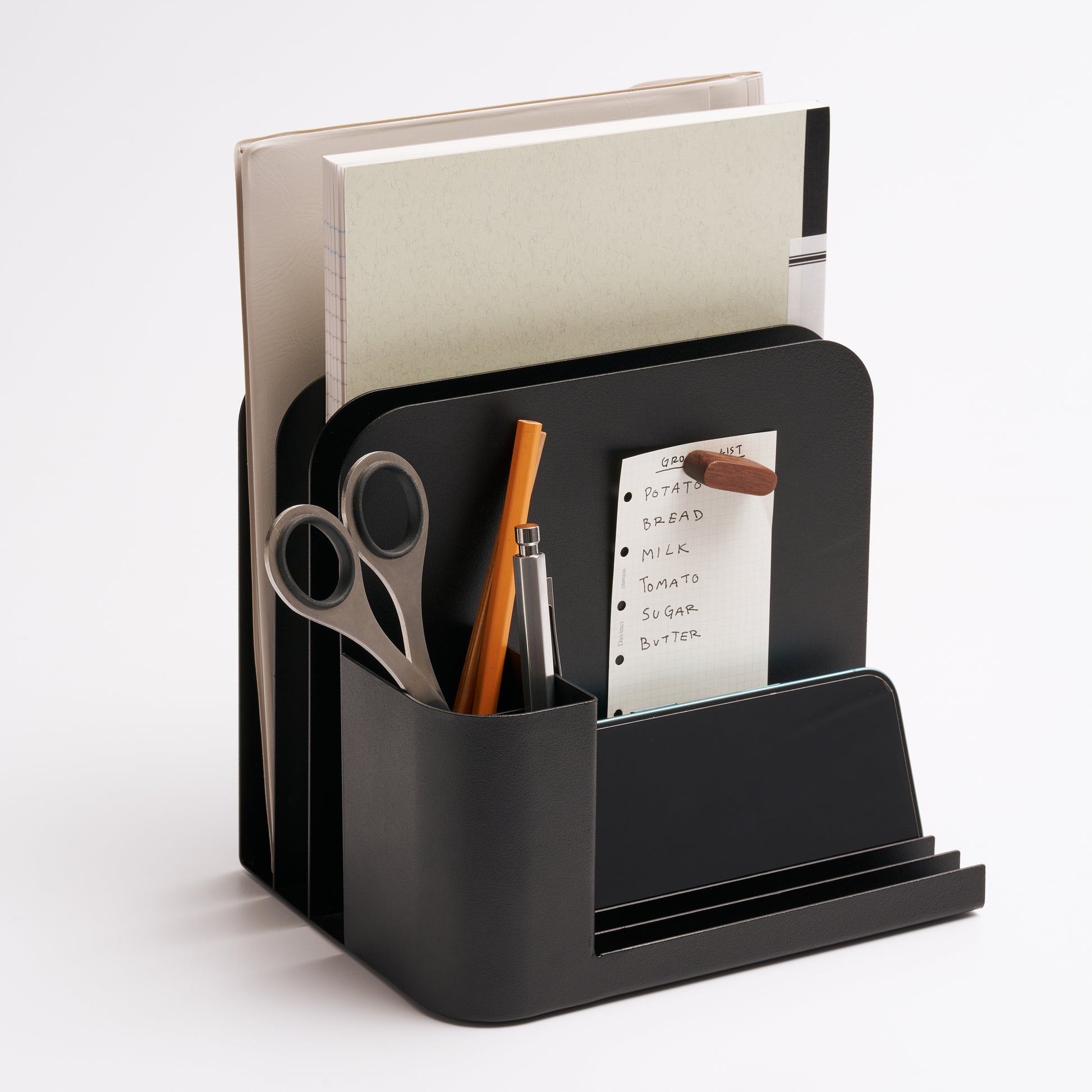 Black steel desk caddy from Apto organizing files, pens, office supplies, and post-its.