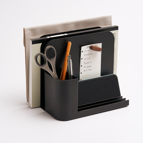 Black steel desk caddy from Apto organizing files, pens, office supplies, and post-its.