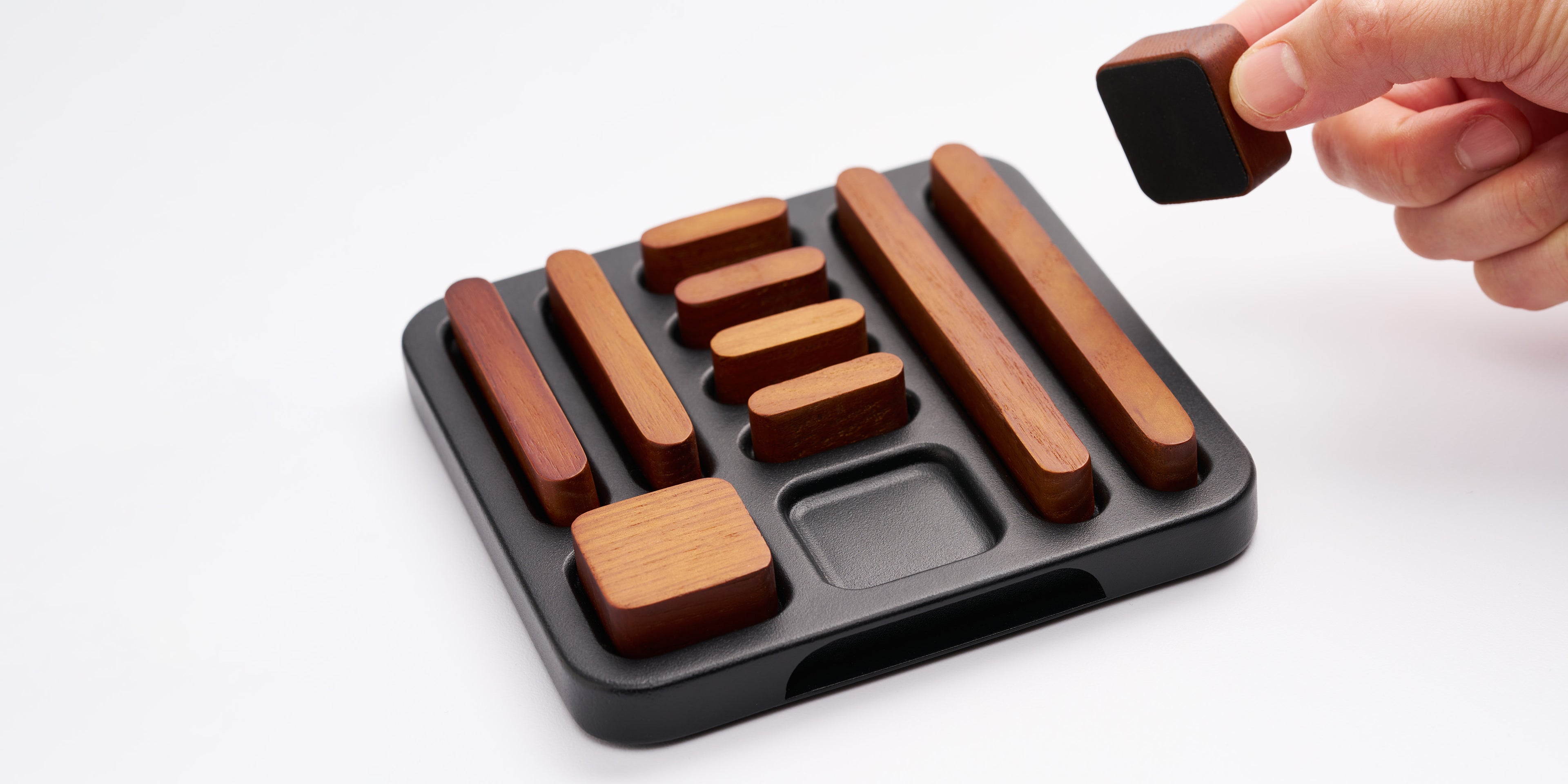 Close-up of tidy magnet set in holder, hand placing one magnet