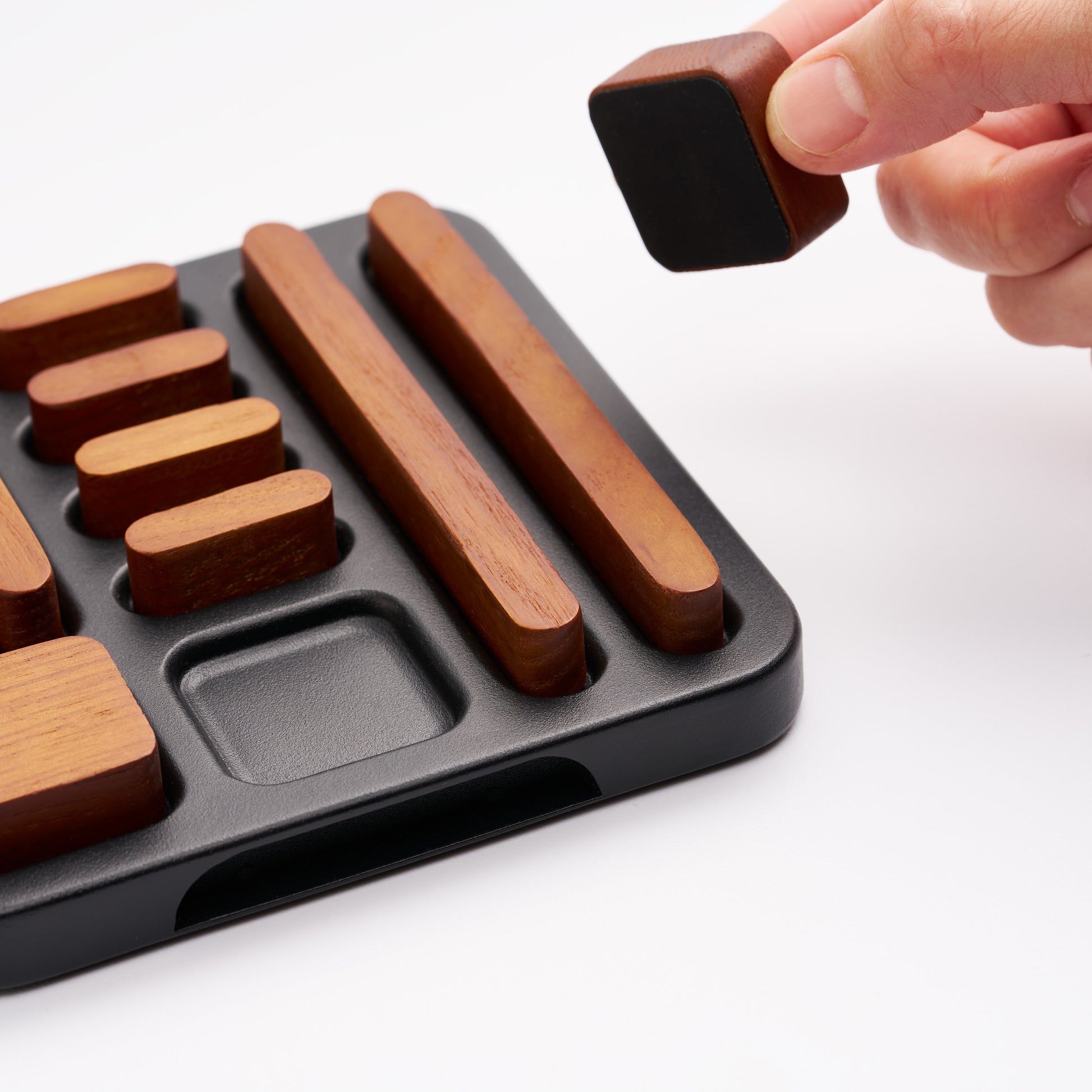 Close-up of tidy magnet set in holder, hand placing one magnet