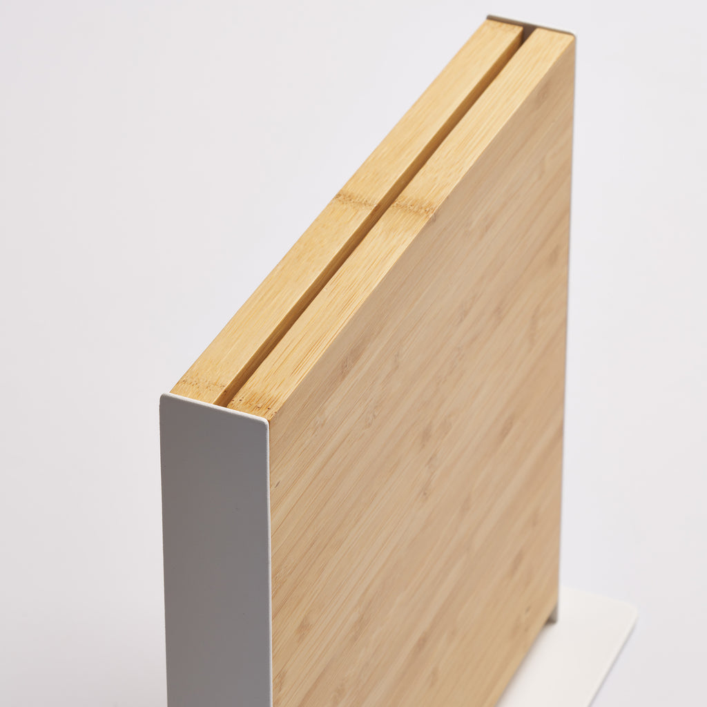 Close-up of the top edge of the Apto Slot Knife Stand, showing the knife slot between two bamboo panels in the white steel frame