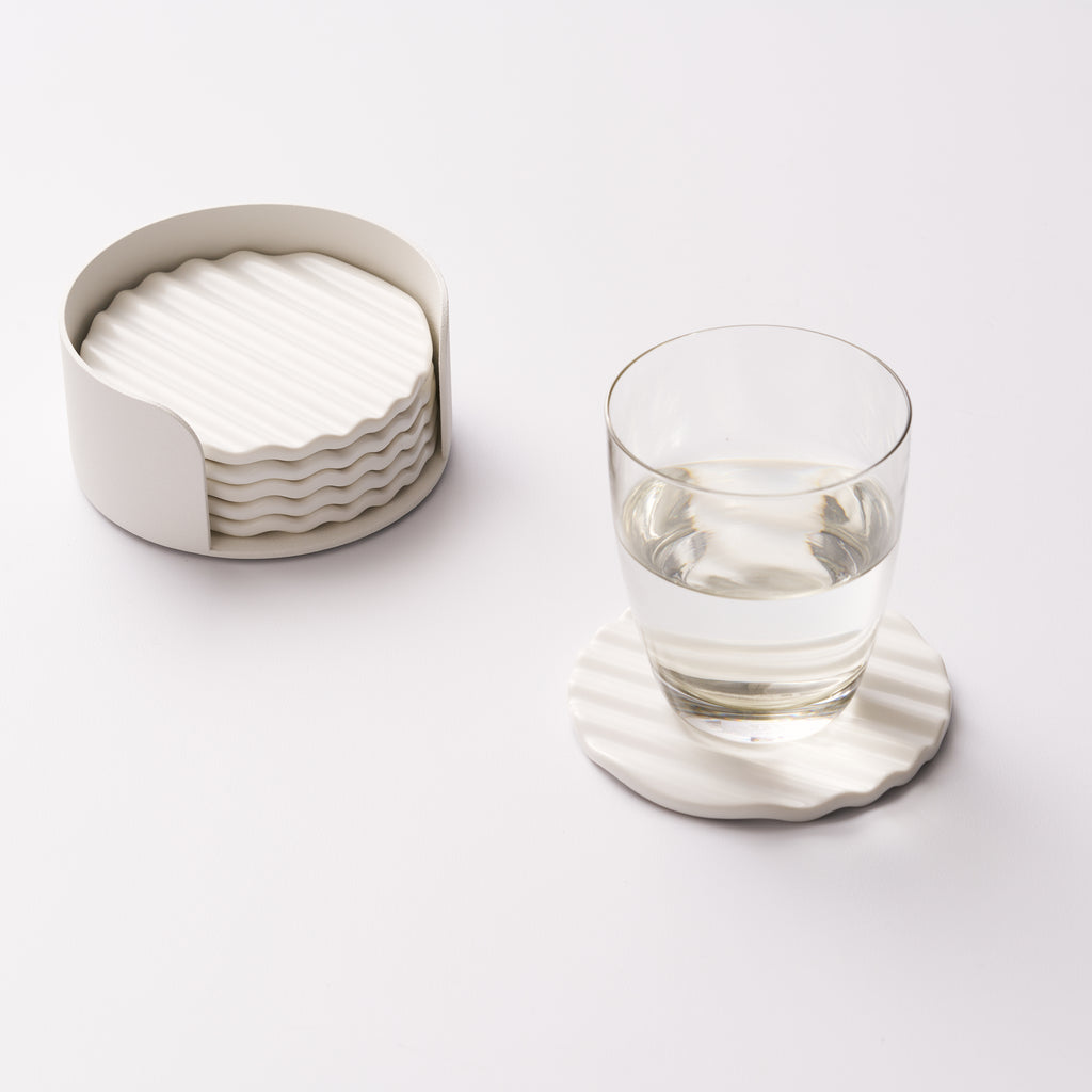 Wave ceramic coaster set in holder with one coaster displayed and holding a glass of water