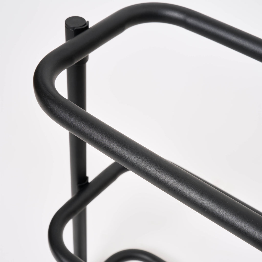 Close-up of the rounded corner on the Apto Obround Shoe Rack Short in black steel, showing the smooth bent tube frame on a white background