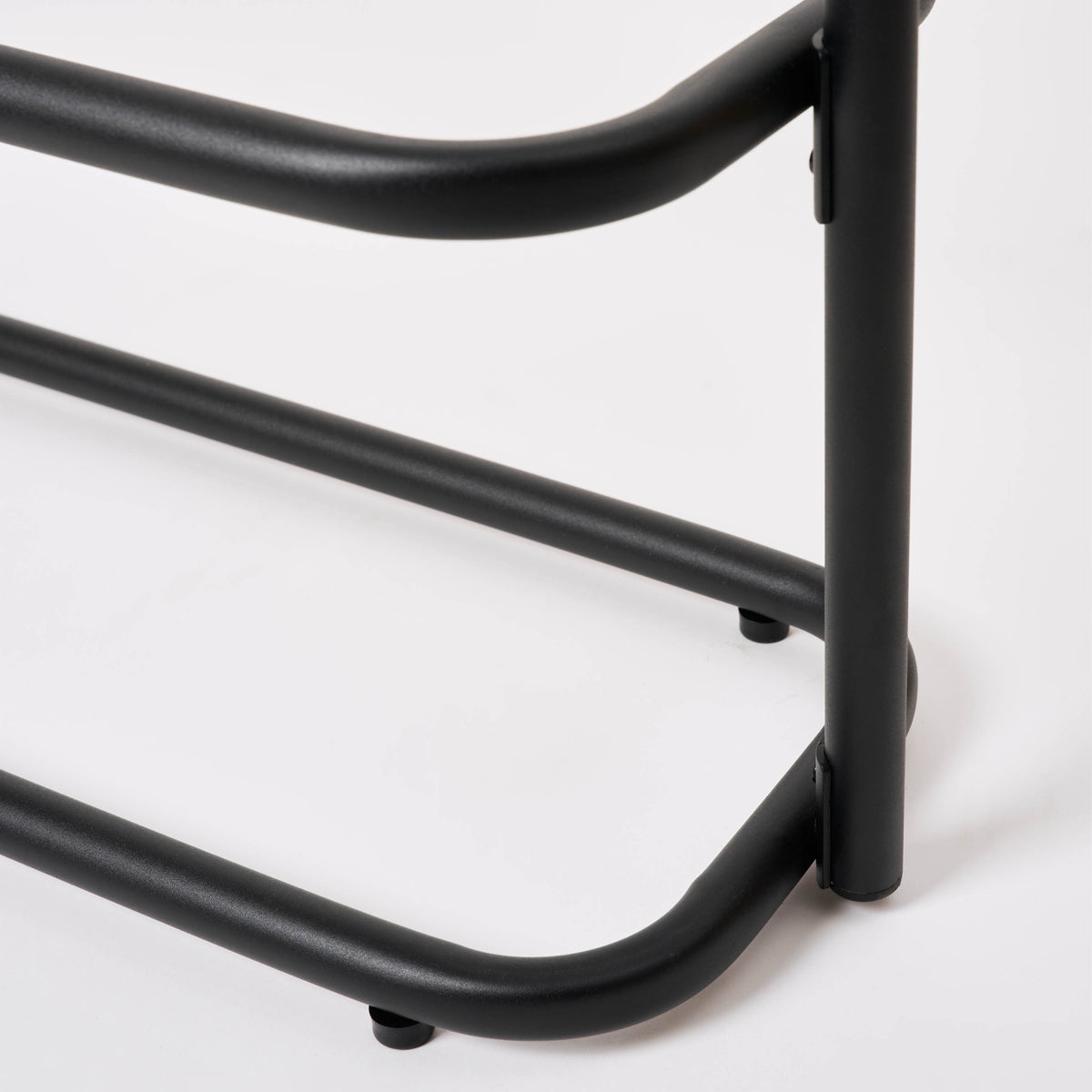 Close-up of a leg and foot pad on the Apto Obround Shoe Rack Short in black steel, showing the bottom tier on a white background