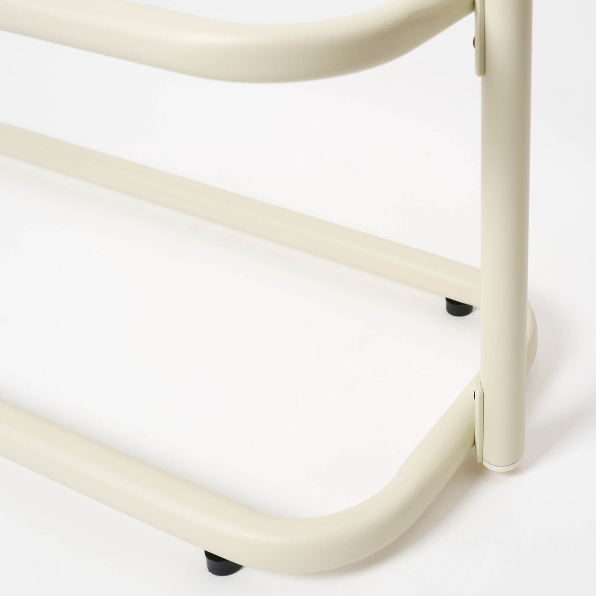 Close-up of a leg and foot pad on the Apto Obround Shoe Rack Short in ivory steel, showing the bottom tier on a white background