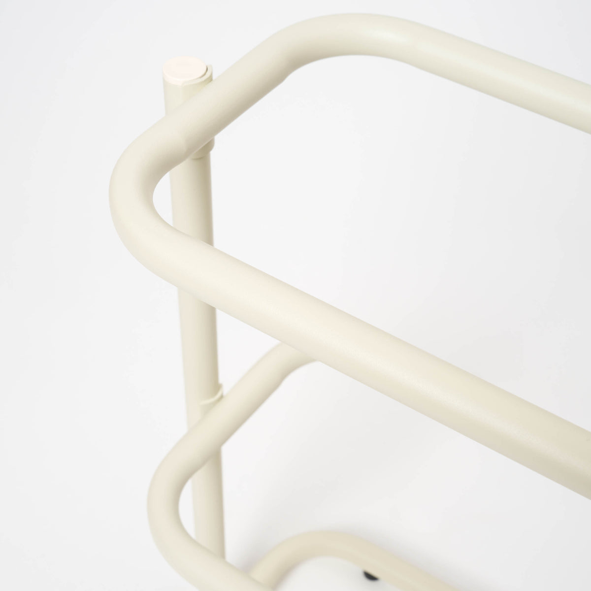 Close-up of the rounded corner on the Apto Obround Shoe Rack Short in ivory steel, showing the smooth bent tube frame on a white background