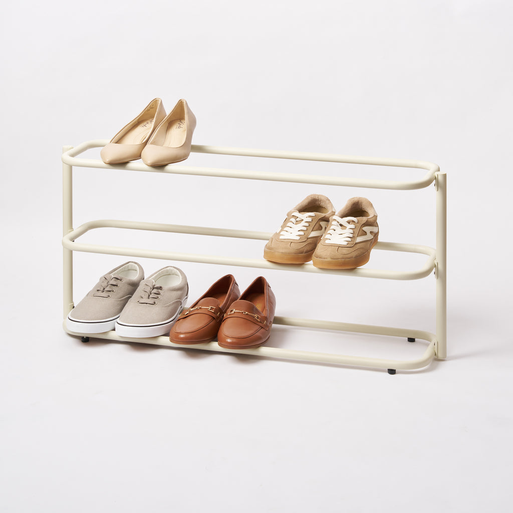 Apto Obround Shoe Rack Short in ivory steel holding heels, sneakers and loafers on three tiers, shown on a plain white background