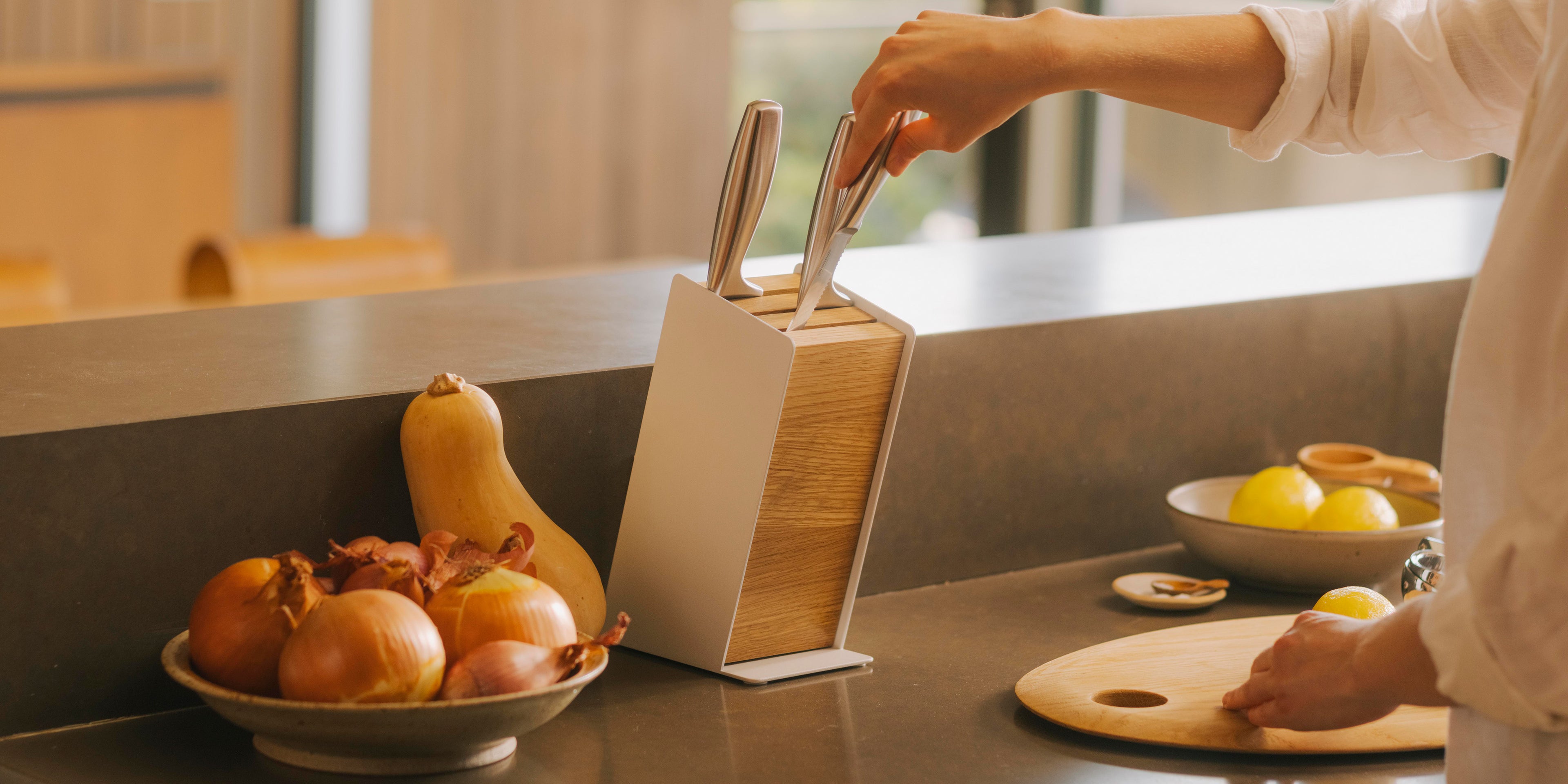 Woman removing knife from modern universal knife block from Apto in a modern kitchen.