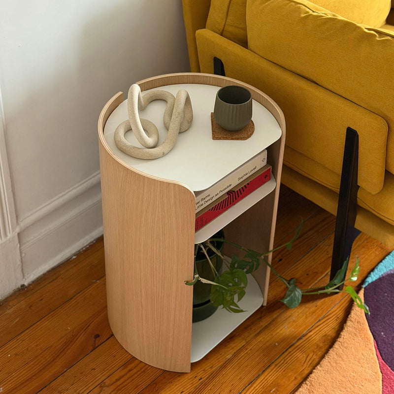 Small round wooden side table with a white top against a yellow sofa.